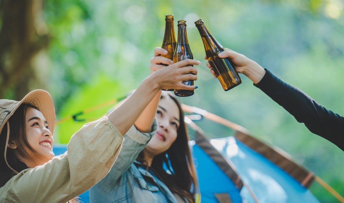 young-woman-girl-friends-travelers-relaxing-camp-chairs-tent-they-are-cheering-drinking-beer-during-camping-talking-with-fun-happy-together-min